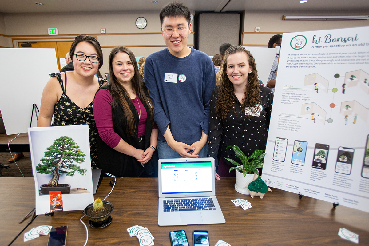 Four students stand with their capstone poster about a project with the Pacific Bonsai museum.