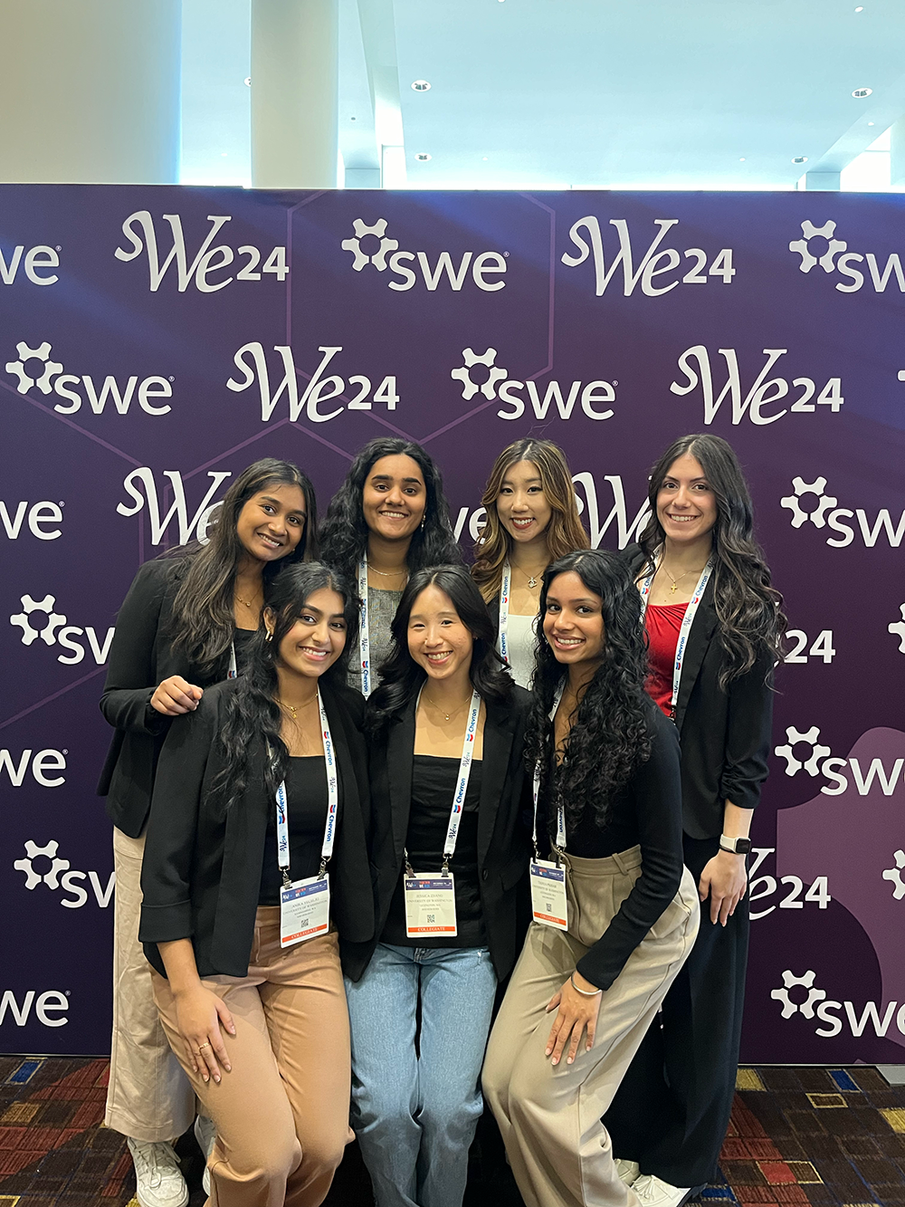 Group of seven students standing in front of SWE banner at SWE conference