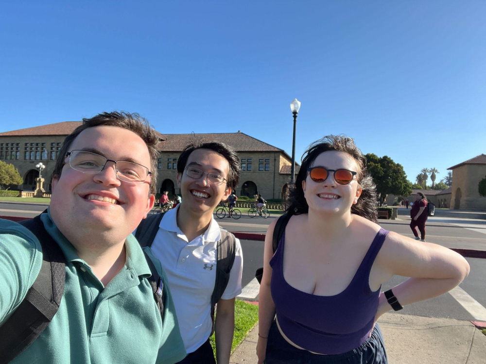 three students smiling at the camera outside of the conference