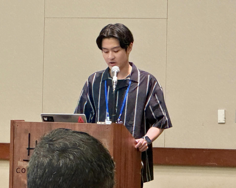 Donghoon Shin standing behind a podium speaking to the room