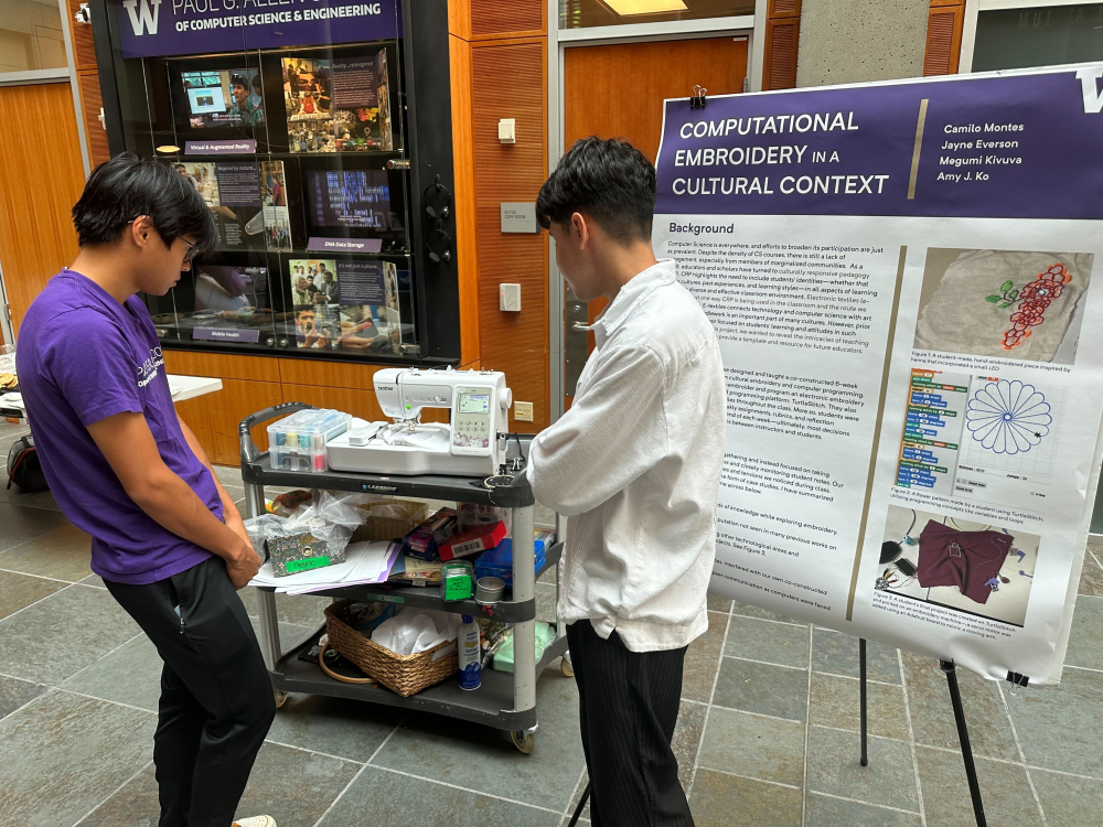 Two students looking at a research poster that is titled Computational Embroidery in a Cultural Context
