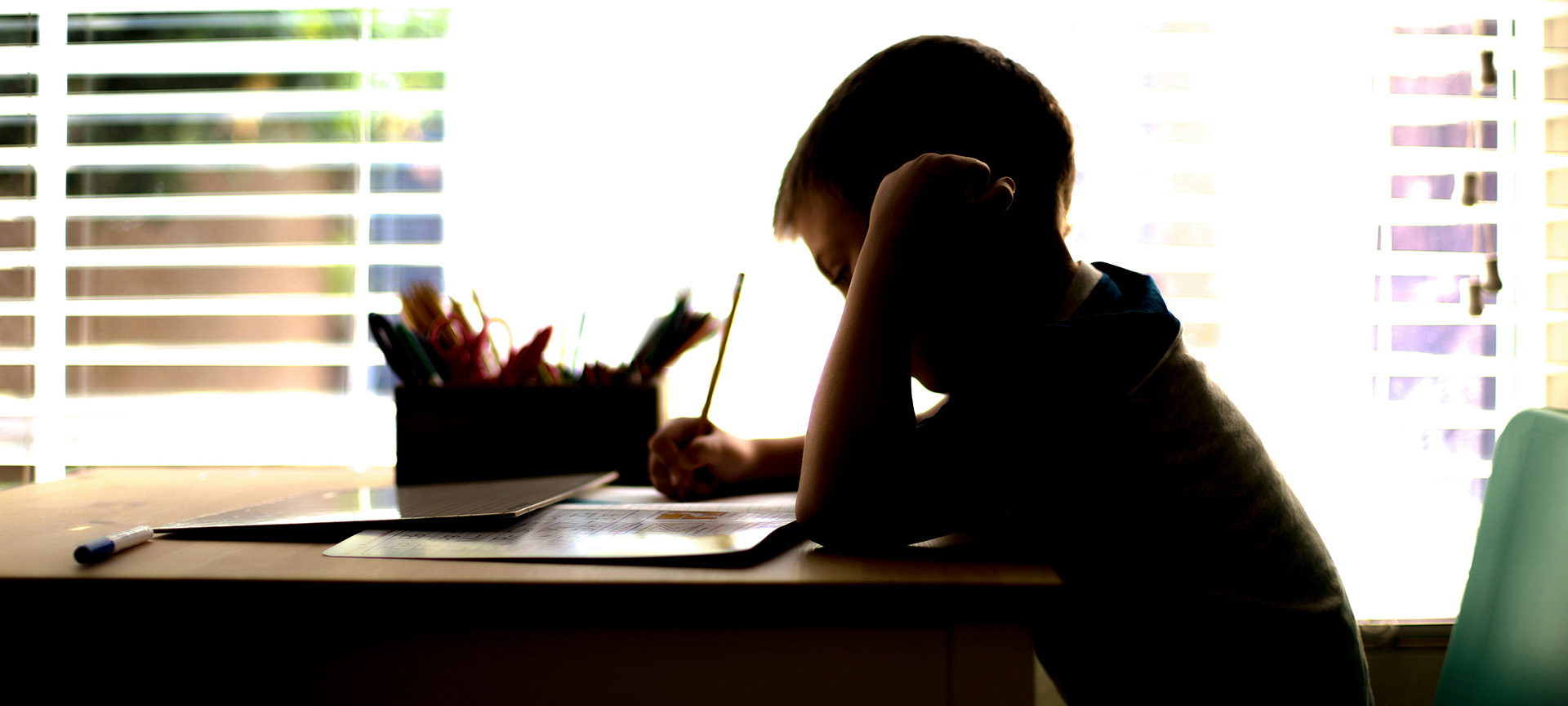 young person sitting at a desk writing with a pencil